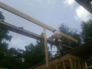 Carpenter setting a ridge beam over a new addition frame — Ice Dam Removal by Roofing Brothers in Wilsall