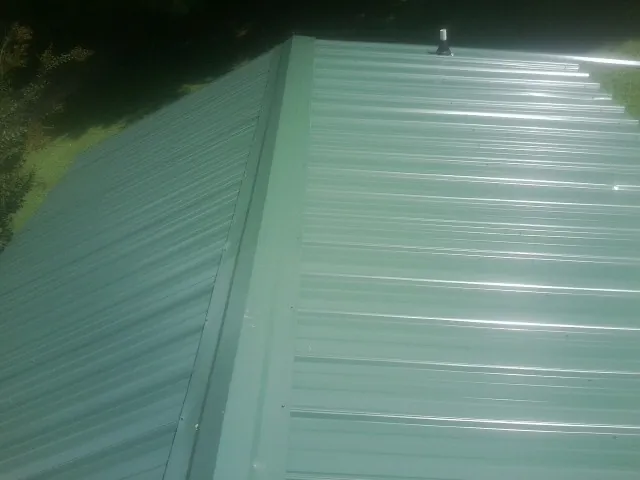 New green metal panels meeting at the ridge of a roof — Flat Roof Repair work by our crew in Wilsall