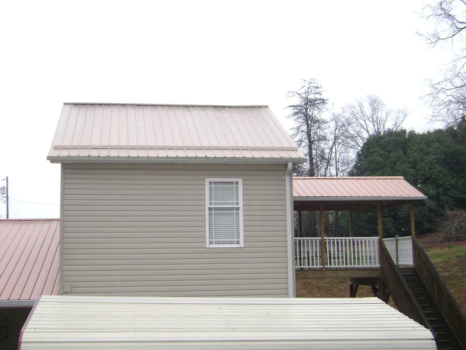 Tan metal roofs on a two story addition and attached porch, from a Roof Replacement job in Wilsall